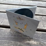 Rozevřené CD Maniac se šedým obalem na dřevěném stole