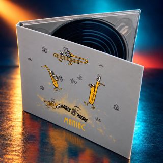 Rozevřené CD Maniac s kreslenými dechovými nástroji na pódiu v záři reflektorů
