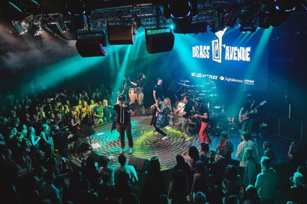 Pódium s logem Brass Avenue v tyrkysovém světle, kolem tančící publikum